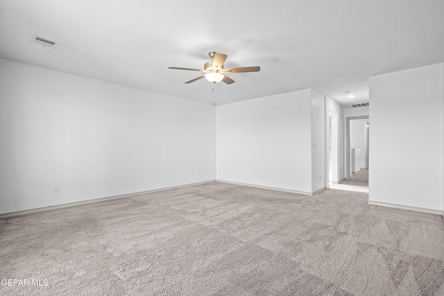 carpeted spare room with baseboards, ceiling fan, and visible vents