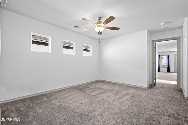 carpeted empty room with baseboards, ceiling fan, and visible vents