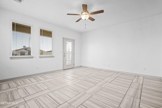 unfurnished room featuring ceiling fan and baseboards