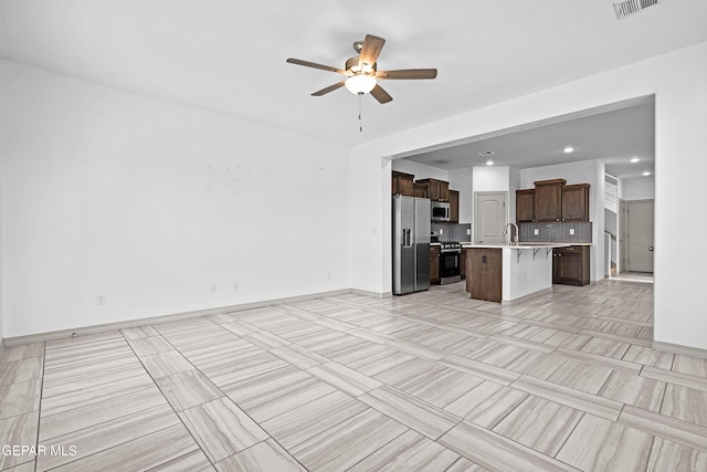 unfurnished living room with light tile patterned flooring, a sink, a ceiling fan, baseboards, and visible vents