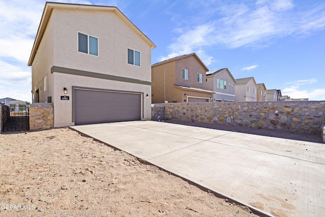 exterior space with fence, a residential view, a garage, stucco siding, and concrete driveway