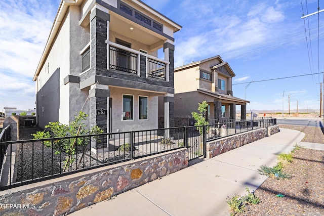 view of front facade featuring stucco siding, fence, and a balcony