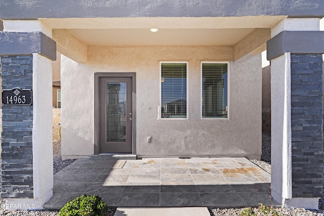 view of exterior entry with a patio and stucco siding