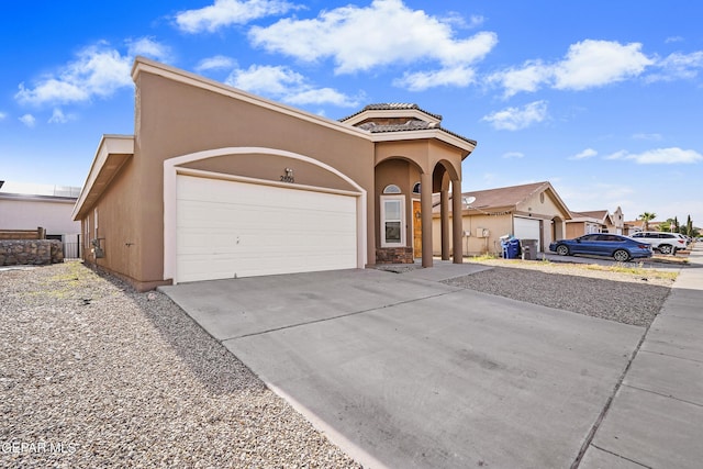mediterranean / spanish home with a garage, stucco siding, concrete driveway, and a tiled roof