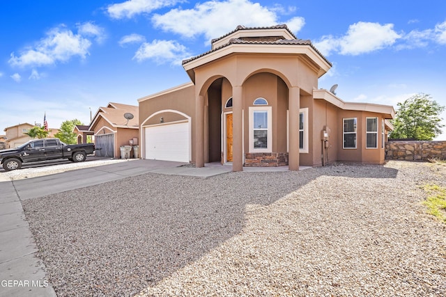 mediterranean / spanish home featuring a garage, stucco siding, and driveway