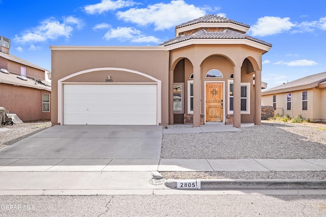 mediterranean / spanish-style home featuring concrete driveway, a garage, a tile roof, and stucco siding