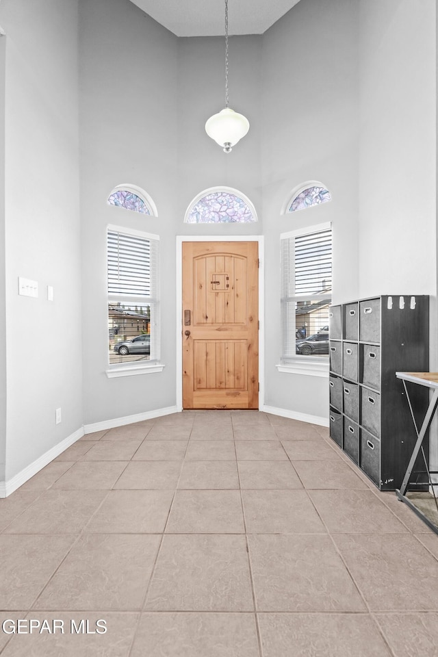 foyer entrance with plenty of natural light, tile patterned flooring, and a towering ceiling