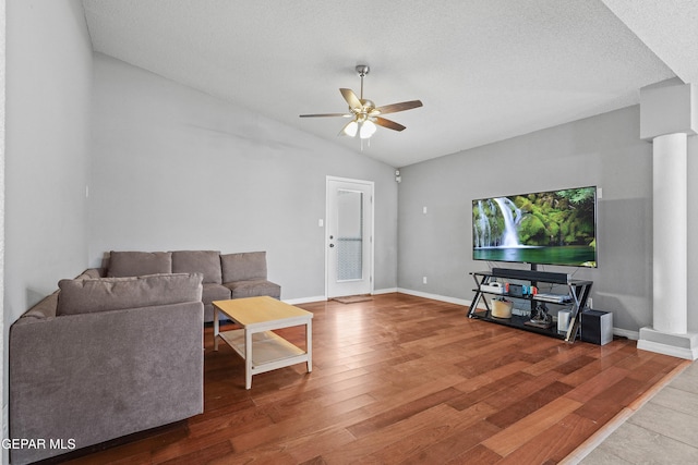 living area with ceiling fan, a textured ceiling, baseboards, wood finished floors, and vaulted ceiling