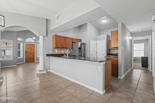 kitchen featuring a sink, stainless steel refrigerator with ice dispenser, a textured ceiling, and visible vents