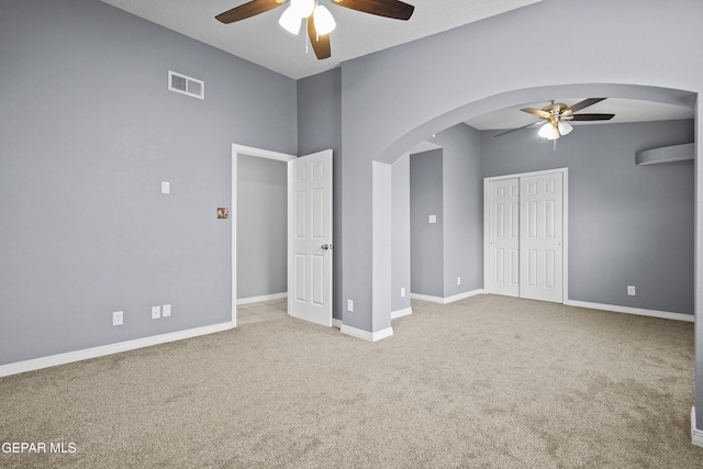 unfurnished bedroom with carpet flooring, arched walkways, baseboards, and visible vents
