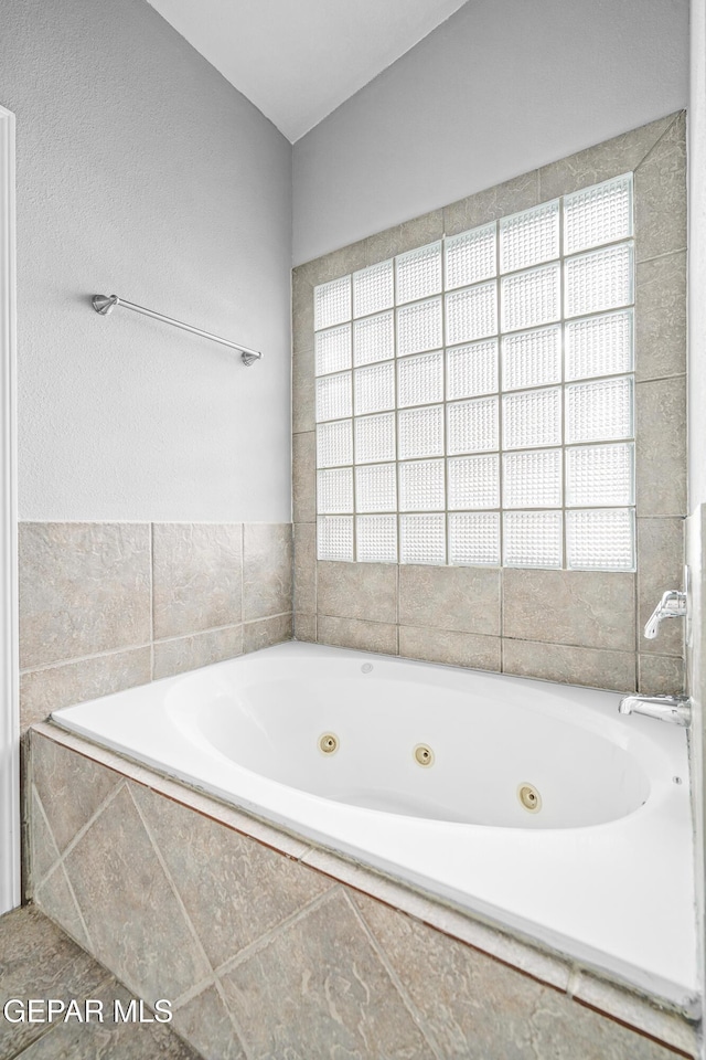 full bathroom with a tub with jets and a healthy amount of sunlight