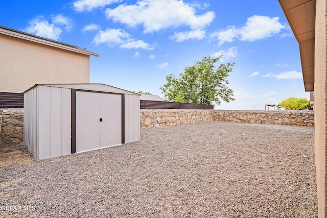 view of yard with an outdoor structure, a fenced backyard, and a storage shed