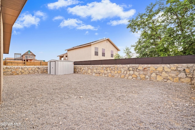 view of yard featuring a fenced backyard, a storage unit, and an outbuilding