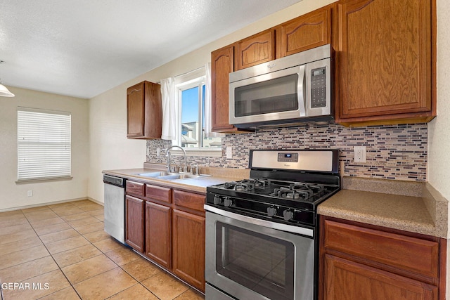 3929 Hueco Valley Dr, El Paso, TX 79938 - kitchen with backsplash, brown cabinets, a sink, stainless steel appliances, and light tile patterned flooring
