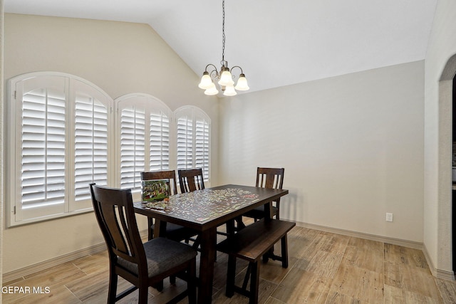 dining space featuring baseboards, vaulted ceiling, light wood-style flooring, and a notable chandelier