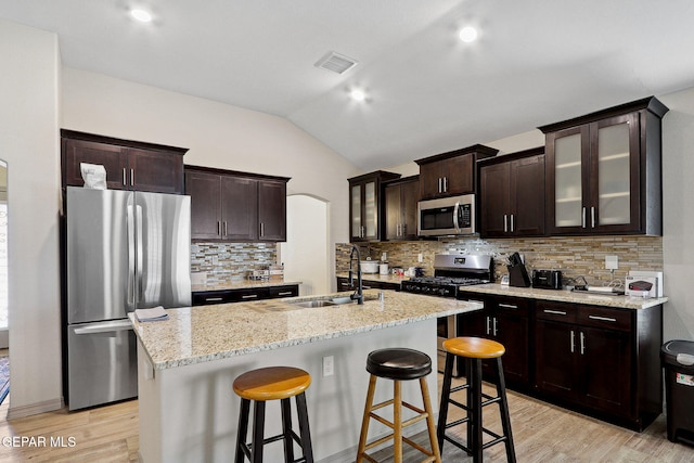 kitchen featuring visible vents, appliances with stainless steel finishes, vaulted ceiling, light wood-type flooring, and a sink