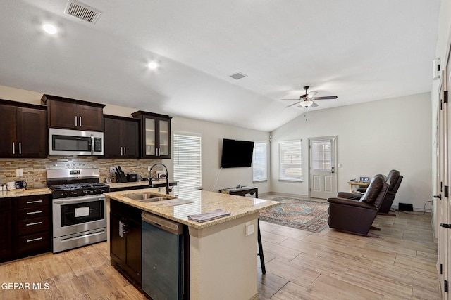 kitchen featuring ceiling fan, appliances with stainless steel finishes, vaulted ceiling, a sink, and open floor plan