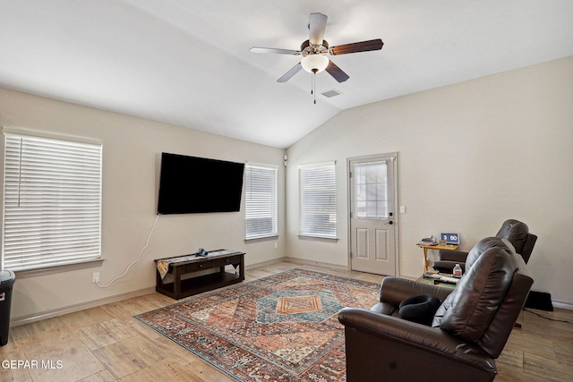 living room featuring visible vents, light wood-style floors, a ceiling fan, baseboards, and vaulted ceiling