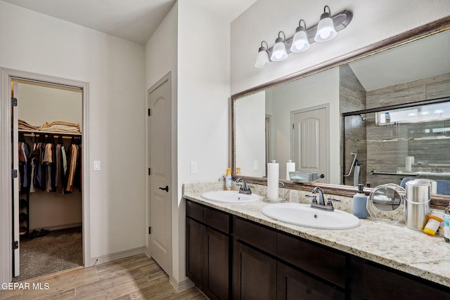 bathroom featuring double vanity, a shower stall, a sink, and wood finished floors