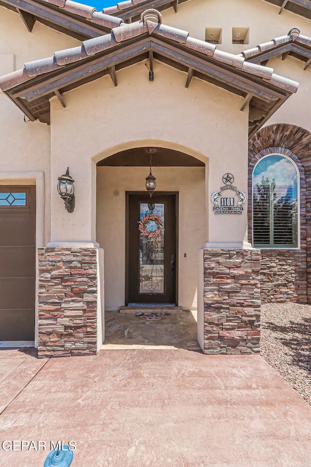view of exterior entry featuring stone siding and stucco siding
