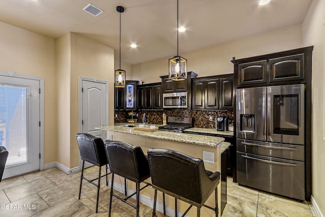 kitchen featuring dark brown cabinets, visible vents, backsplash, appliances with stainless steel finishes, and a kitchen island