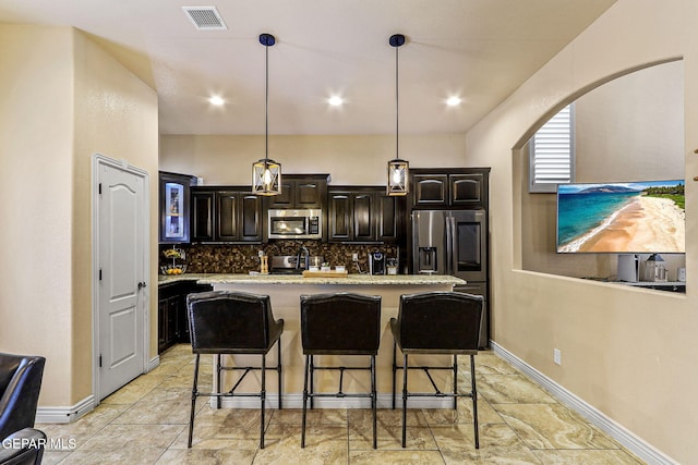 kitchen featuring a breakfast bar area, a center island, stainless steel appliances, visible vents, and backsplash