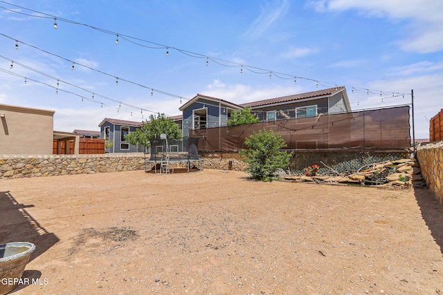 back of property with a trampoline and a fenced backyard