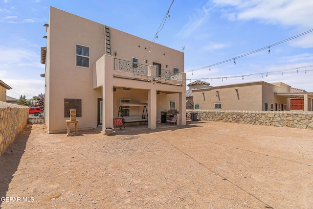 back of house with a balcony, a patio area, stucco siding, and fence
