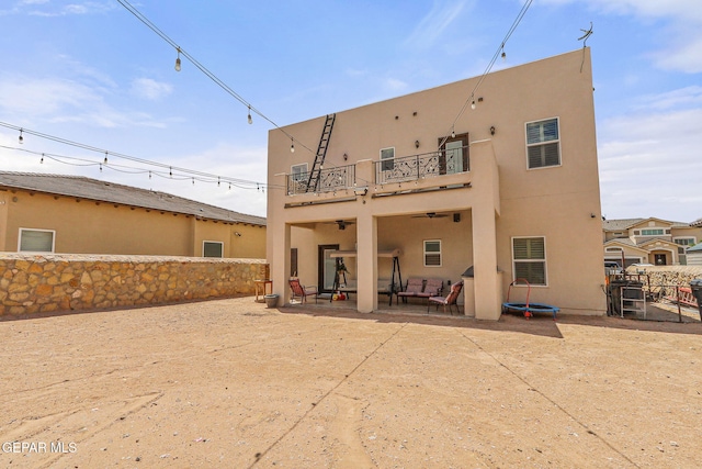 back of house with a balcony, a patio, ceiling fan, stucco siding, and a fenced backyard