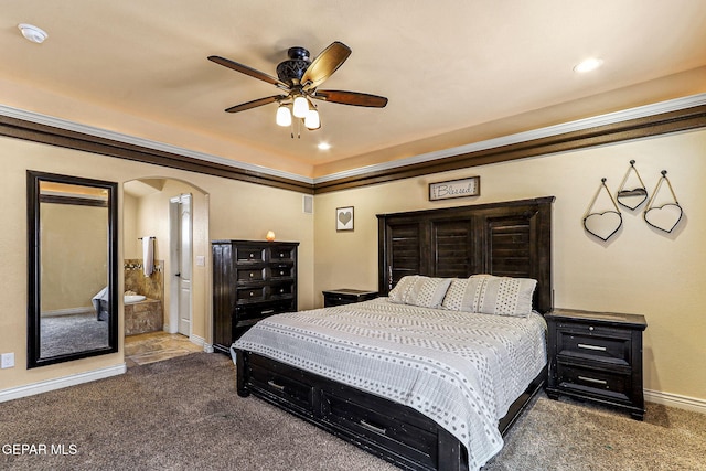 carpeted bedroom with a ceiling fan, recessed lighting, baseboards, ensuite bathroom, and arched walkways