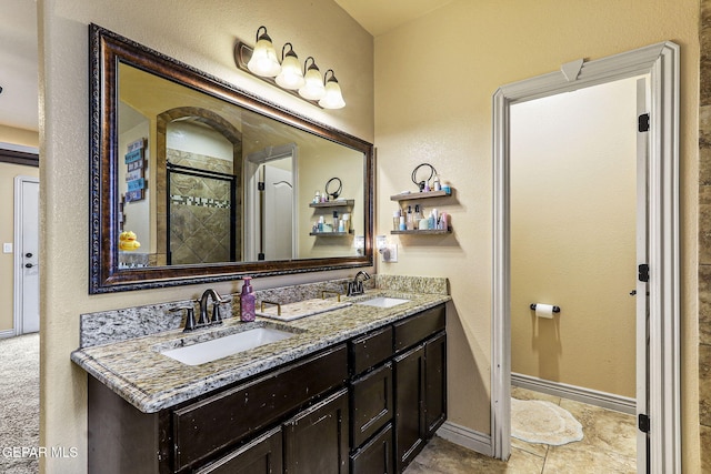 full bathroom featuring double vanity, baseboards, tiled shower, and a sink