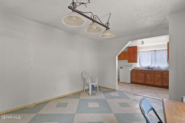 12365 Stubbs Dr, San Elizario, TX 79849 - unfurnished dining area featuring a textured ceiling, washer / dryer, baseboards, and light floors
