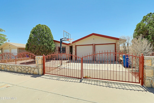 exterior space featuring concrete driveway, a gate, a fenced front yard, and an attached garage