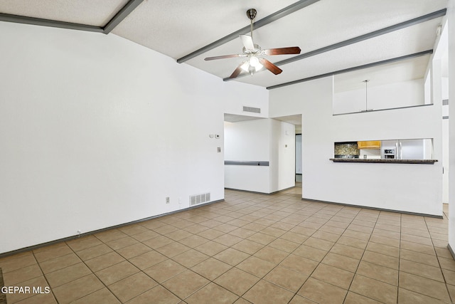 unfurnished living room with baseboards, ceiling fan, visible vents, and vaulted ceiling with beams