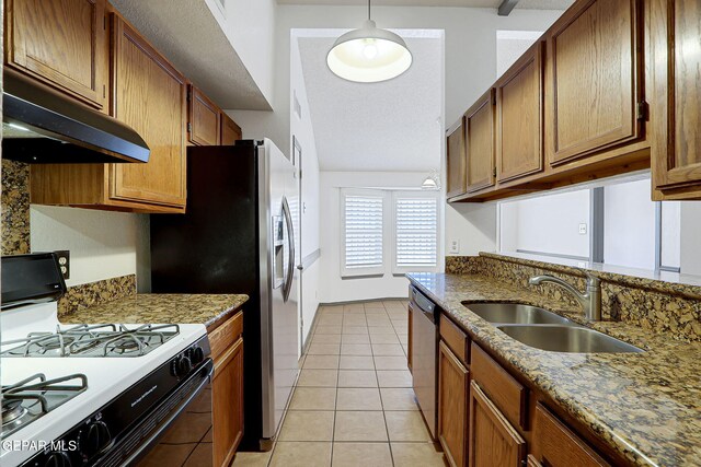 kitchen featuring brown cabinetry, range with gas stovetop, under cabinet range hood, a sink, and light tile patterned floors