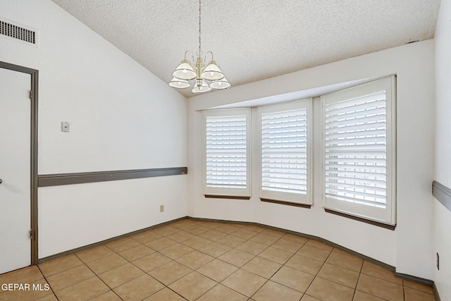 empty room featuring a textured ceiling, visible vents, vaulted ceiling, light tile patterned floors, and a chandelier