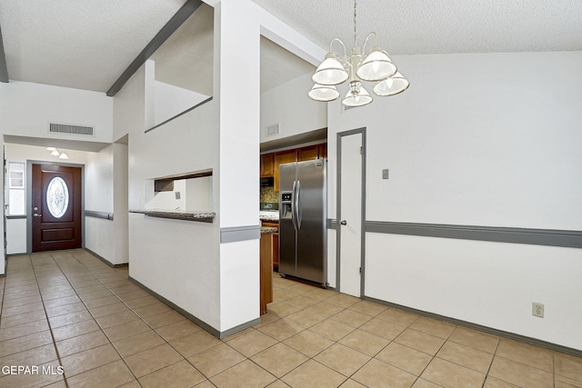 kitchen featuring stainless steel refrigerator with ice dispenser, a notable chandelier, visible vents, and a textured ceiling