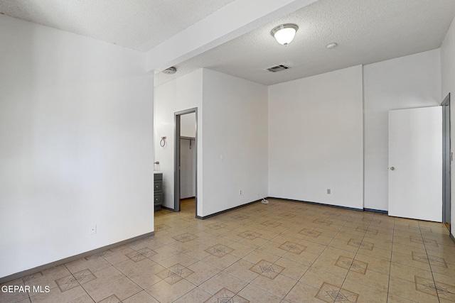 unfurnished room featuring a textured ceiling, visible vents, and baseboards