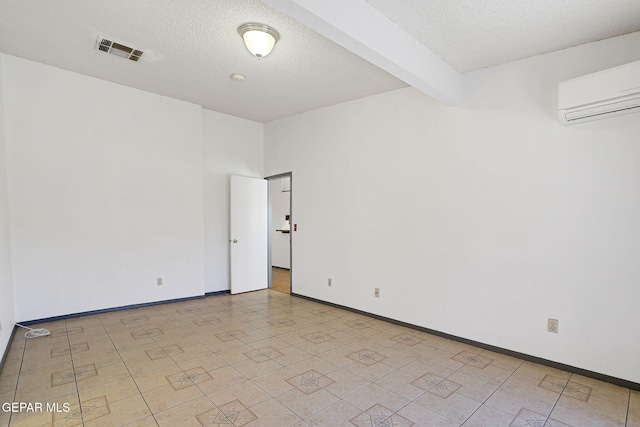 unfurnished room featuring visible vents, beam ceiling, baseboards, a wall mounted air conditioner, and a textured ceiling