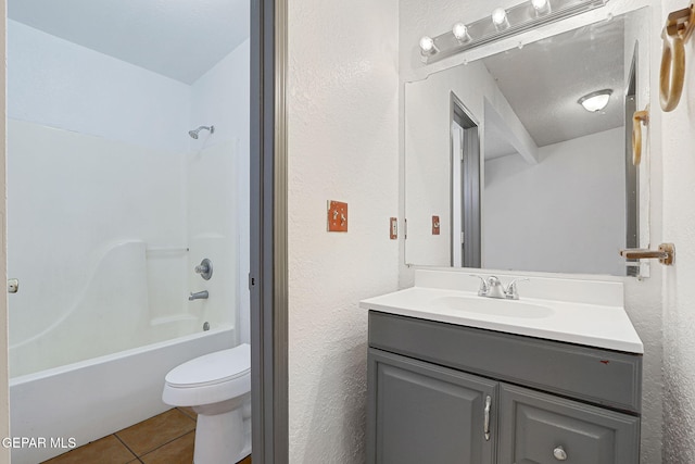 bathroom with vanity, a textured wall, toilet, washtub / shower combination, and tile patterned floors