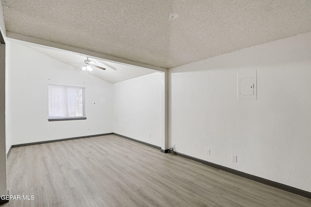 spare room featuring ceiling fan, a textured ceiling, wood finished floors, baseboards, and lofted ceiling