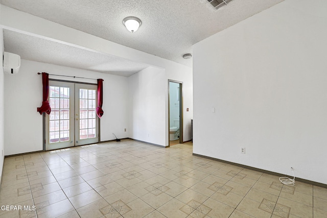 empty room with visible vents, baseboards, a textured ceiling, a wall unit AC, and french doors