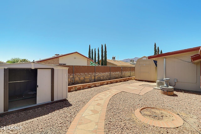 view of yard featuring a storage unit, a fenced backyard, a patio area, and an outbuilding