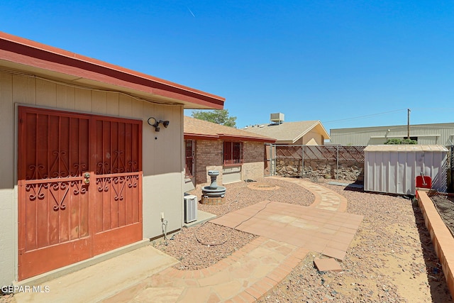 view of patio with fence private yard, a shed, and an outbuilding