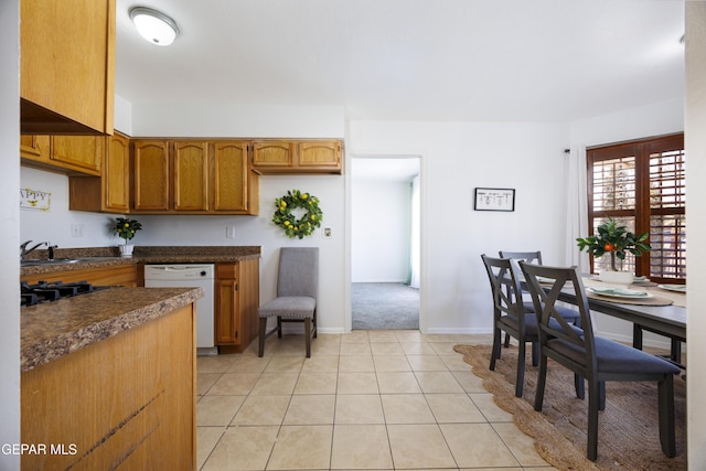 9232 Morelia Rd, El Paso, TX 79907 - kitchen with white dishwasher, brown cabinetry, baseboards, dark countertops, and light colored carpet