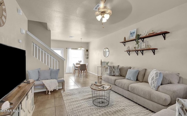 living room with light tile patterned floors, baseboards, a ceiling fan, and stairs