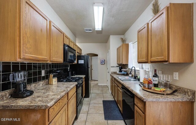 kitchen featuring visible vents, decorative backsplash, light tile patterned flooring, a sink, and black appliances