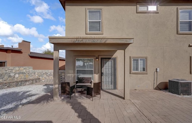 back of house with central air condition unit, a patio, an outdoor hangout area, and stucco siding