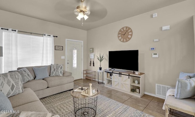 living area featuring tile patterned floors, baseboards, a ceiling fan, and visible vents