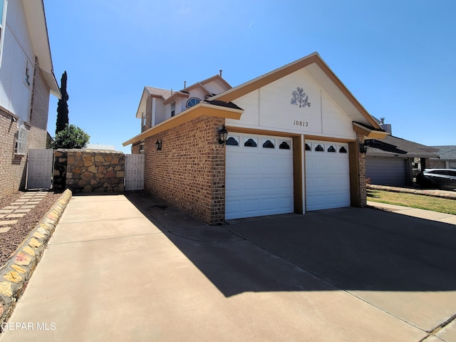 10812 Sandy Koufax Dr, El Paso, TX 79924 - exterior space featuring concrete driveway, brick siding, a gate, and a garage